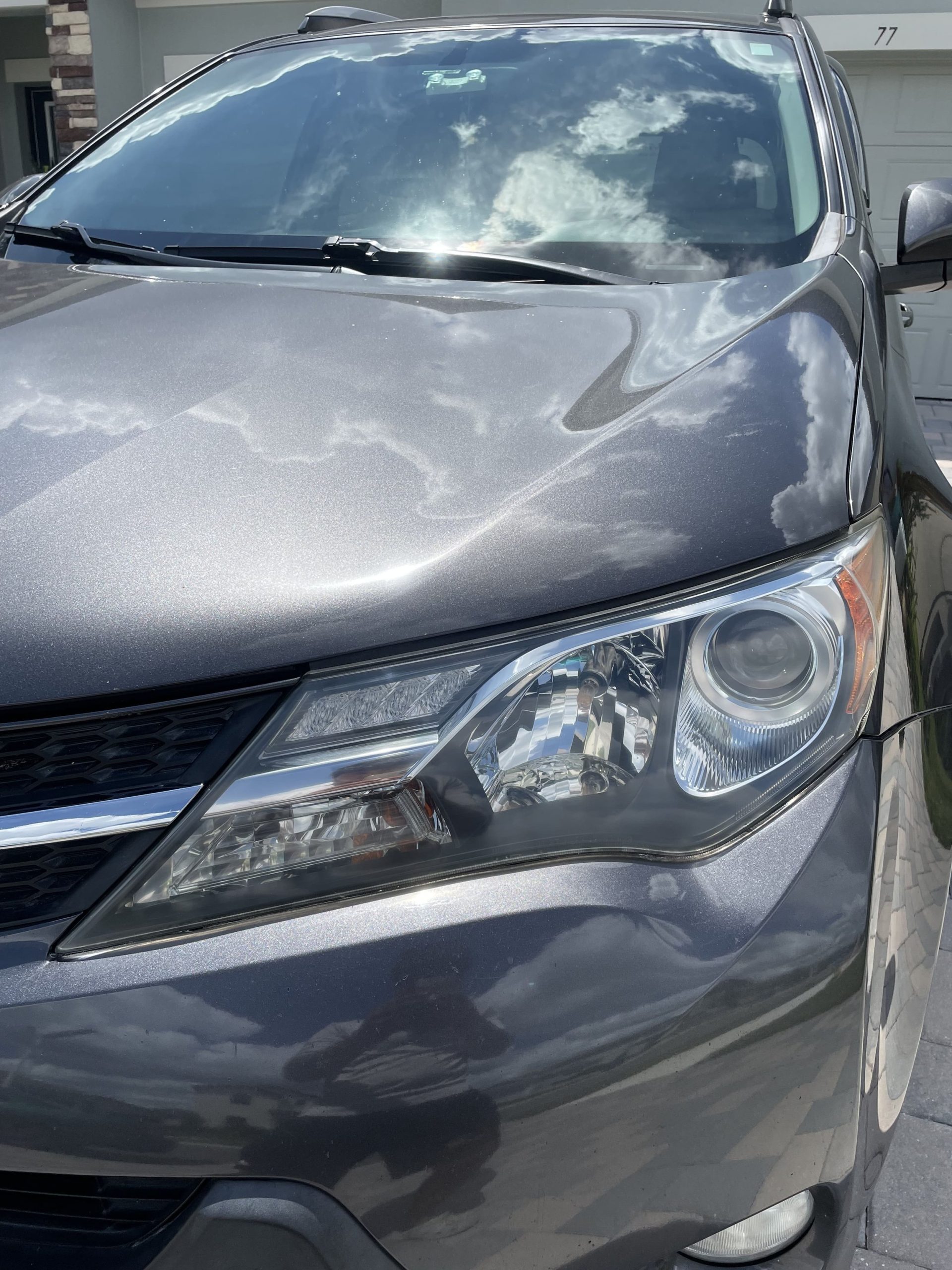 Close-up of restored headlight on dark gray sedan in Lutz